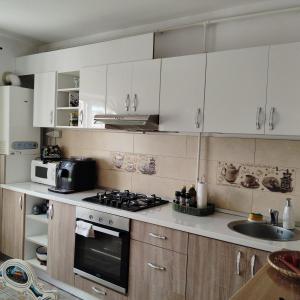 cocina con armarios blancos, fogones y fregadero en Vintage Central Apartament, en Târgu Jiu