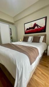 a bedroom with a large white bed with a painting on the wall at Diamond of Skopje Luxury apartment 19th floor in Skopje