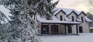a house with snow covered trees in front of it at Gościniec Szpakówka in Czeremcha