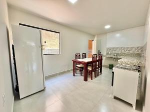 a kitchen and dining room with a table and a refrigerator at La casa de 3 suítes em Guriri - equipada para 8 pessoas in São Mateus