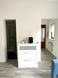 a white dresser in a room with a bathroom at Cozy Airport Apartment in Kelsterbach