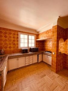a large kitchen with orange tiles on the walls at Villa Dune Rouge de la Siesta in Mohammedia