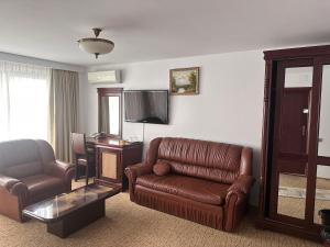 - un salon avec un canapé en cuir et une chaise dans l'établissement Hotel Bliss, à Bucarest