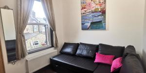 un sofá de cuero negro en una sala de estar con ventana en Beautiful London home sleeps 6, 2 minutes to metro, en Londres