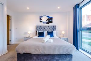 um quarto com uma grande cama branca com almofadas azuis em Sterling Suite - Modern 2 Bedroom Apartment in Birmingham City Centre - Perfect for Family, Business and Leisure Stays by Dreamluxe em Birmingham