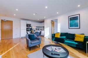 a living room with a green couch and a table at Sterling Suite - Modern 2 Bedroom Apartment in Birmingham City Centre - Perfect for Family, Business and Leisure Stays by Dreamluxe in Birmingham