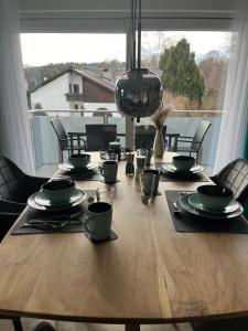 a wooden table with plates and utensils on it at Luxurious apartment with mountain views in Prien am Chiemsee
