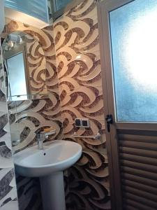 La salle de bains est pourvue d'un lavabo et d'un papier peint en tourbe. dans l'établissement Oasis appart sérénité, à Marrakech