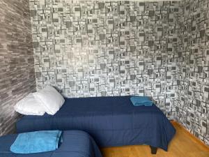 um quarto com uma cama e uma parede com uma parede de tijolos em victoria em Porvenir
