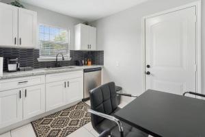 cocina con armarios blancos, mesa y sillas en Cozy Two Bedroom Home Minutes from Downtown! en Houston