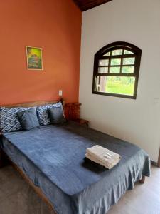 1 dormitorio con 1 cama con edredón azul y ventana en Fazenda Piloes en Itaipava