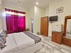 een slaapkamer met een bed, een dressoir en een televisie bij Hotel Haridarshan Opposite Golden Temple in Amritsar