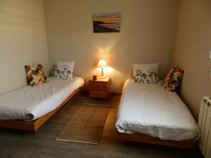 2 Betten in einem Zimmer mit einer Lampe auf einem Tisch in der Unterkunft La Rosée Dar - Villa avec piscine in Martin-Église