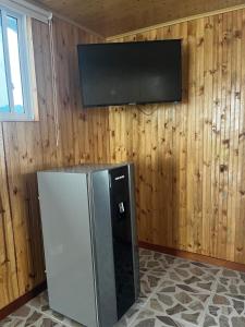 einen Kühlschrank mit einem Flachbild-TV an der Wand in der Unterkunft El paraiso glamping in Villavicencio