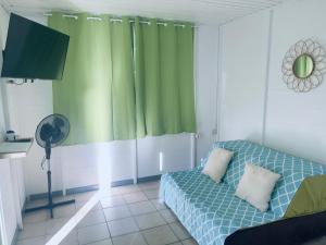 Tuatahi Beach Lodge في بوناويا: غرفة معيشة مع أريكة وستارة خضراء