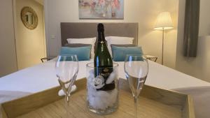 - une bouteille de vin et 2 verres à vin sur le lit dans l'établissement B&B SPA CITADELLE, à Namur