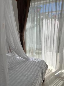 a bed with a white canopy and a window at Robinson Beach Bungalow in Vinh Hoa