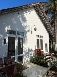 a white house with chairs and a table at Robinson Beach Bungalow in Vinh Hoa