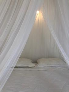 Robinson Beach Bungalow في Vinh Hoa: سرير أبيض مع مظلة ووسادتين