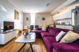 a living room with a purple couch and a kitchen at [5 min walk from subway] Elegant & Modern in Milan