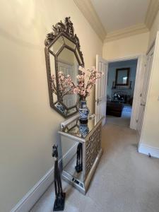 a vase on a glass table with a mirror on a wall at Coral Gables in Northampton