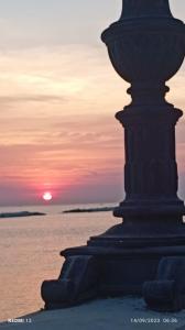 a sunset over the water with a large statue at Amalò Guest House in Bari