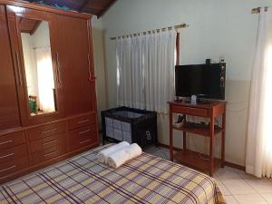 a bedroom with a bed and a tv and a table at Casa Azul em Búzios in Búzios