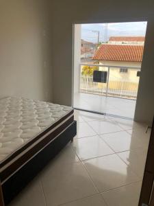 a bed in a room with a large window at Casa Conceição da Barra temporada e Carnaval in Conceição da Barra