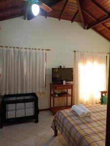 - une chambre avec un lit, une télévision et une fenêtre dans l'établissement Casa Azul em Búzios, à Búzios