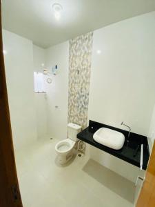 a white bathroom with a toilet and a sink at Casa Conceição da Barra temporada e Carnaval in Conceição da Barra