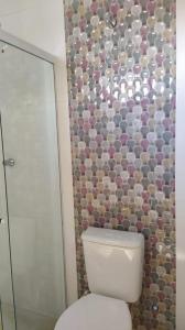 a bathroom with a toilet and a tiled wall at Casa Conceição da Barra temporada e Carnaval in Conceição da Barra