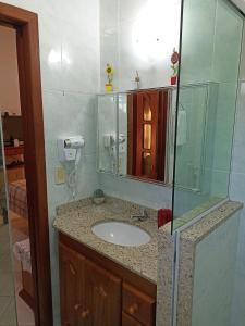 La salle de bains est pourvue d'un lavabo et d'une douche en verre. dans l'établissement Casa Azul em Búzios, à Búzios