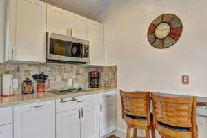 a kitchen with white cabinets and a clock on the wall at Spanish Village Siesta Villa in Port Aransas