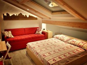 a bedroom with a bed and a red couch at Ad Alba di Canazei una finestra sulla Marmolada in Alba di Canazei +13 photos