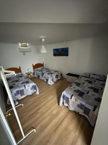 a room with three beds and a wooden floor at Casa Mari in Sanlúcar de Barrameda