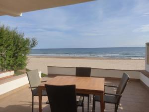 Apartament Tere في أوليفا: طاولة وكراسي خشبية على الشاطئ