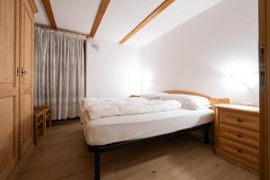 a bedroom with a bed and a dresser and a window at Cesa alla Cascata in Canazei