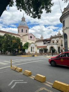 un coche rojo conduciendo por una calle frente a un edificio en Dpto Catedral en Salta