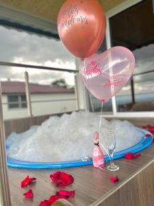 a table with two balloons and a bottle and glasses at El paraiso glamping in Villavicencio