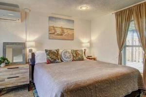 Un dormitorio con una cama grande y un espejo. en Spanish Village Sunshine Cottage, en Port Aransas