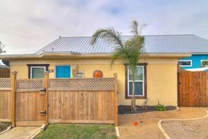 una casa con una valla de madera y una palmera en Spanish Village Sunshine Cottage, en Port Aransas