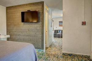 1 dormitorio con 1 cama y pared con TV en Spanish Village Sunshine Cottage, en Port Aransas