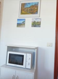 um micro-ondas numa prateleira com fotografias na parede em Apartamento Sobreira en centro Allariz con WIFI em Allariz