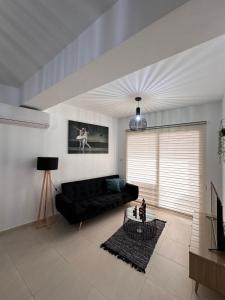Una sala de estar con un sofá negro y una mesa. en Lucy's holidays apartment, en Peyia