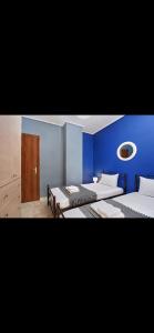 a room with two beds and a blue wall at Cozy apartment next to the port! in Piraeus
