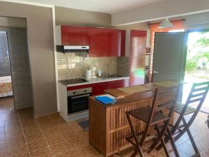 a kitchen with red cabinets and a table and chairs at Bas de villa ensoleillé ventilé in Morne-à-lʼEau