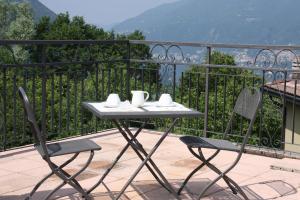 un balcón con una mesa con tazas y sillas en B&B Le Magnolie, en Faggeto Lario 