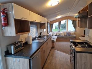 a kitchen and living room with a couch in a caravan at MemoryMakersHoliday Buena Vista in Chwilog