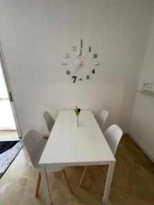 een witte tafel met stoelen en een klok aan de muur bij PIT STOP Apartment in Busto Arsizio