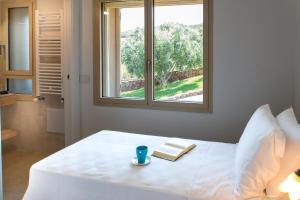 Dormitorio con cama con ventana y libro en Villa Dune di Scivu, en Portixeddu